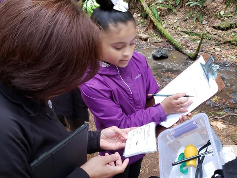 young girl with a clipboard reporting data from her forest educational program to her supervisor