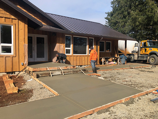 concrete pad drying outside in the sun with two construction workers