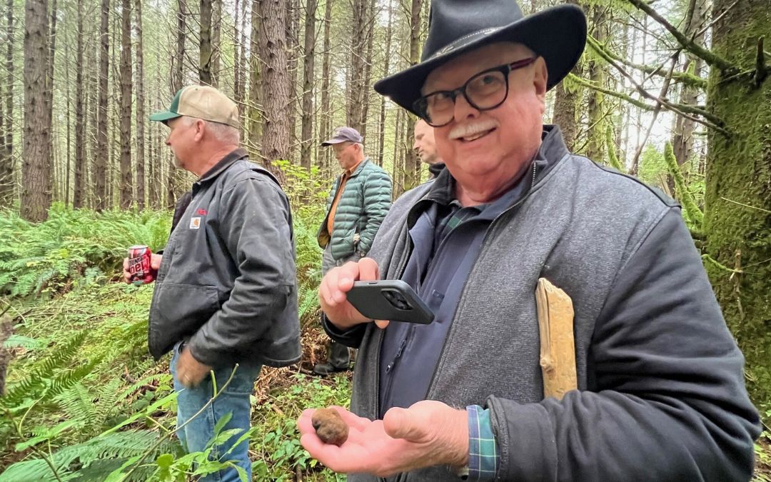 Bob and the Hopkins Demonstration Forest Board at Peedee Woodlands - holding a truffle in the woods with a lush green understory